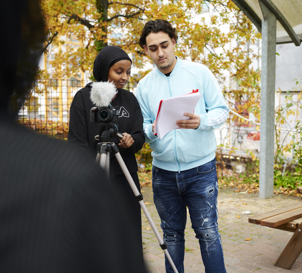 To glade elever står bad et videokamera
