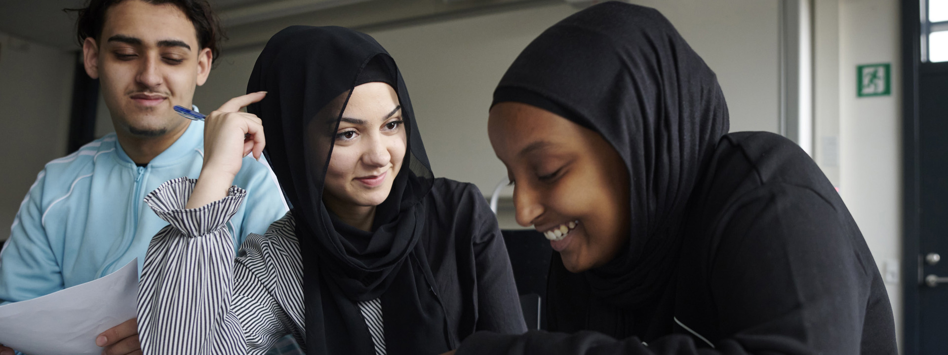 Tre glade elever arbejder sammen