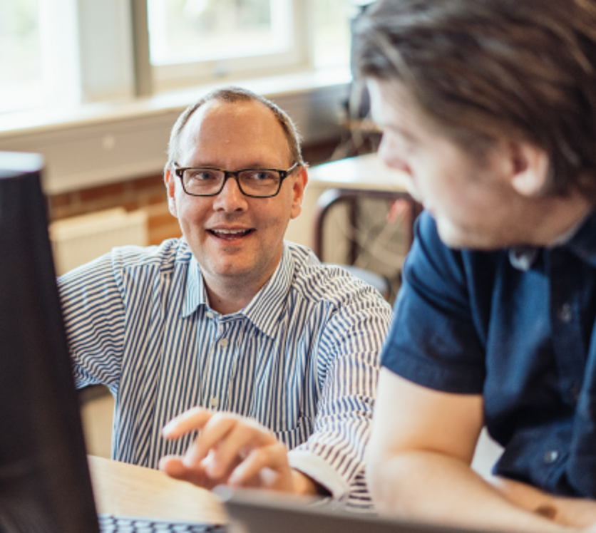Elev får hjælp af glad underviser på computeren