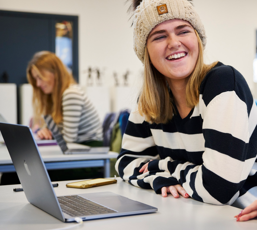Smilende elev sidder bag sin computer