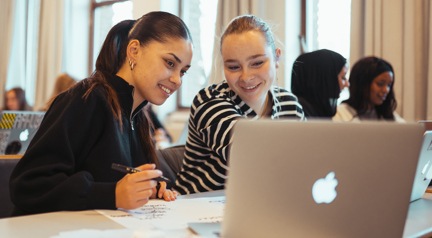 To smilende elever arbejeder sammen på en computer