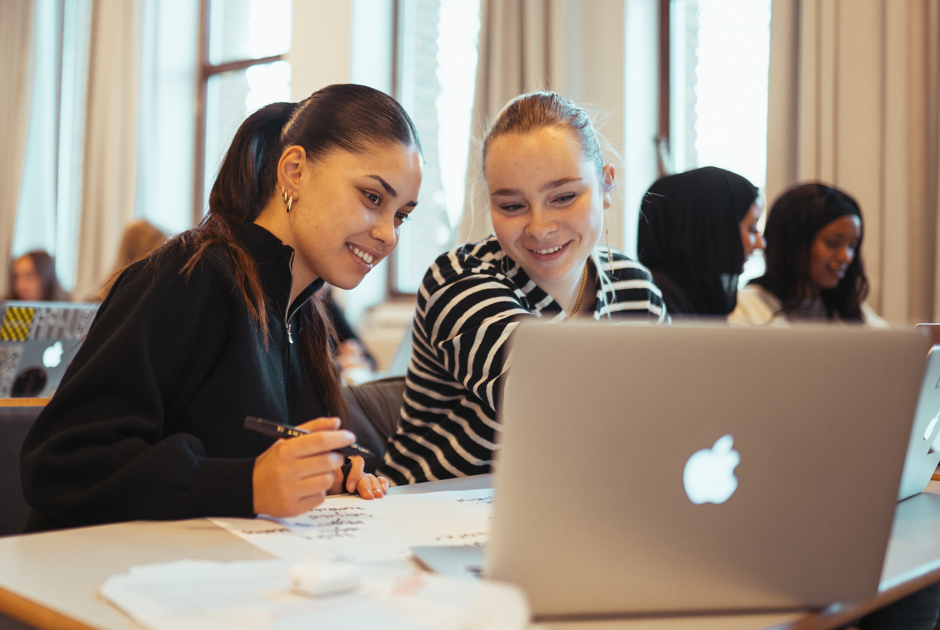 To smilende elever arbejeder sammen på en computer