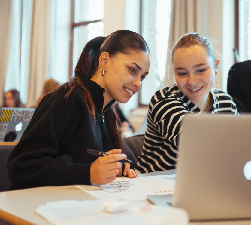 To smilende elever arbejeder sammen på en computer