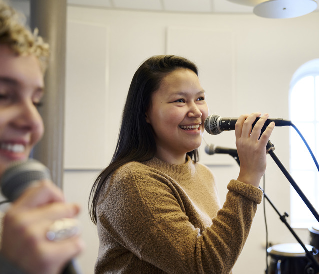 To glade elever synger ind i mikrofoner